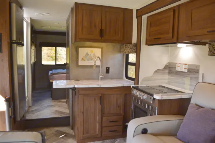 Inviting RV rental interior showcasing a full kitchen, comfortable living space, and a view of the separate bedroom.. Forest River Sunseeker Classic 2021