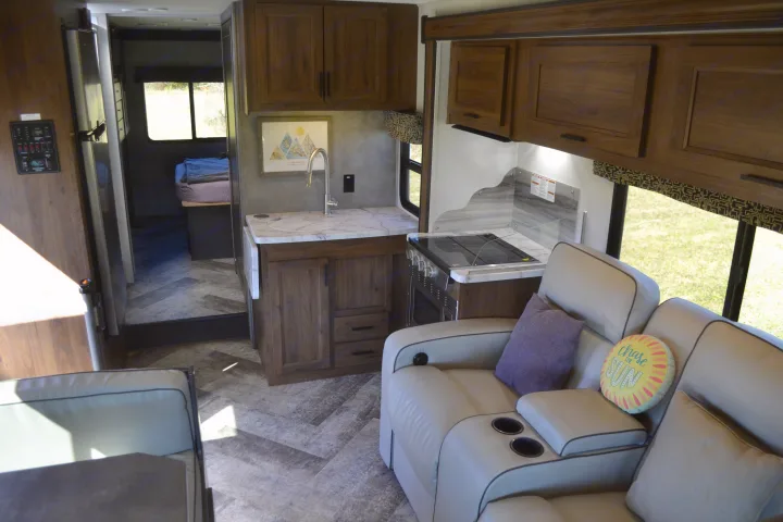 Explore this modern rv rental interior, featuring a full kitchen, cozy living space, and private bedroom setup.. Forest River Sunseeker Classic 2021