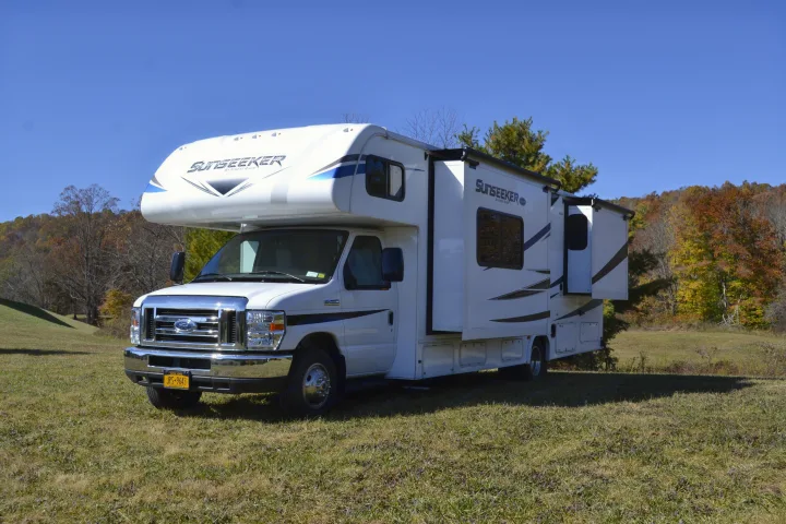 White Sunseeker rv rental, a Class C motorhome, is parked with slide-outs extended in a beautiful autumn landscape.. Forest River Sunseeker Classic 2021