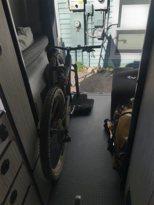 RV rental interior shows a mounted mountain bike, sleeping area, and adventure gear for active travel.. Winnebago Revel 2023
