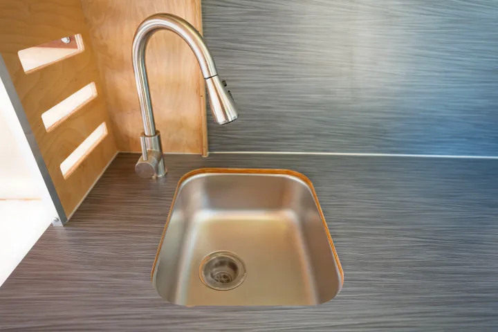 Modern stainless steel sink and faucet on a sleek countertop in a compact RV rental interior.. RAM ProMaster 2022