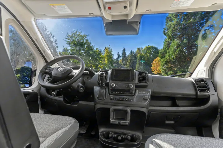 RV rental interior view: dashboard, steering wheel, and front passenger area of a modern camper van.. RAM ProMaster 2022