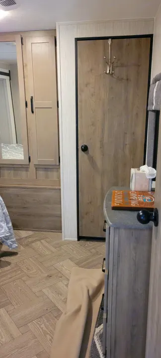RV rental bedroom area featuring modern light wood cabinetry, herringbone floor, and convenient hooks.. Palomino RBFQ 2022