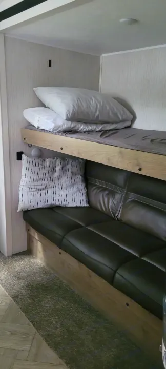 RV rental interior featuring cozy bunk beds above a dark sofa, perfect for sleeping or relaxing.. Palomino RBFQ 2022
