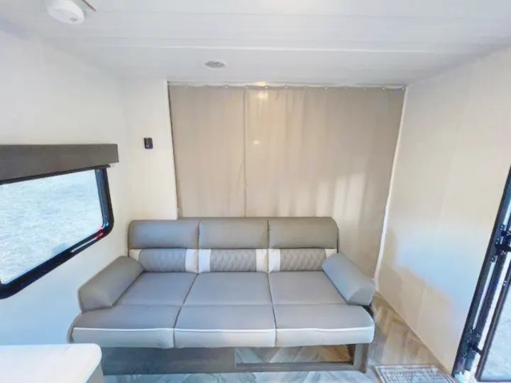 RV rental interior with a modern grey sofa, window, and a full privacy curtain for the rear bed area.. Forest River EVO Select 268 BH 2022