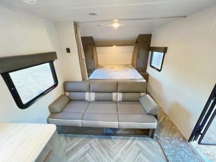 This RV rental interior features a cozy bed at the rear, a comfortable sofa, and windows, making it ideal for travel.. Forest River EVO Select 268 BH 2022