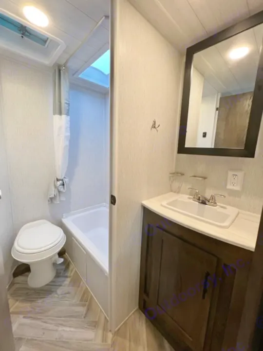 This clean RV rental features a compact bathroom with a modern vanity, sink, mirror, toilet, and shower.. Forest River EVO Select 268 BH 2022