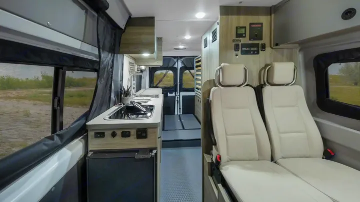 Step into this well-equipped rv rental. Features a full kitchen, comfortable seating, and scenic outdoor views through windows.. Winnebago Solis 2021