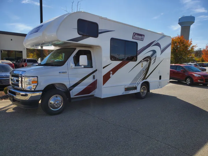 Bright white Coleman Class C rv rental on a sunny day. Front based on a Ford E-350 chassis, parked on asphalt.. Thor Coleman 2023