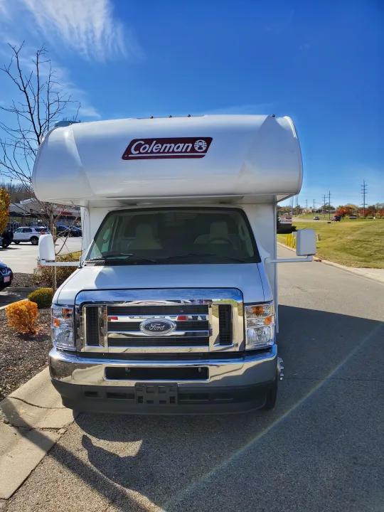 Front view of a white Coleman RV rental on a Ford chassis under a clear blue sky. Ready for your next road trip adventure!. Thor Coleman 2023