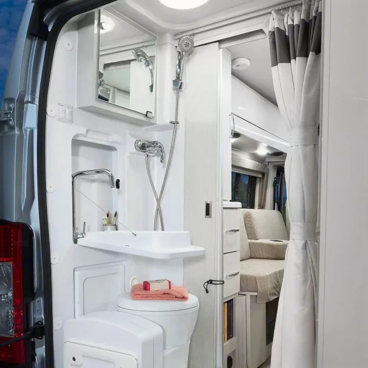 Compact RV rental bathroom: fold-down sink, toilet, shower. Beyond, comfy living space. Ideal for mobile adventures.. Thor Rize 2022