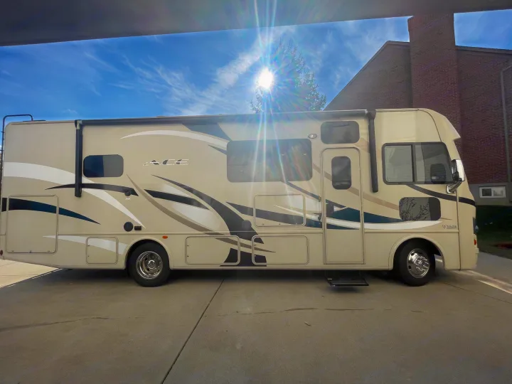 Sunny day Class A RV rental ready for adventure. Parked on concrete with blue sky & bright sun.. Thor A.C.E. 2017