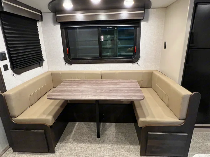 Modern RV rental dinette featuring light-toned U-shaped booth seating, wood-look table, and windows.. Crossroads RV Cruiser Aire 2022