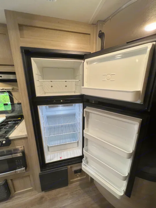 Clean, open refrigerator and freezer in an RV rental kitchen, ready for your adventure.. Coachman Catalina Catalina Summit Series 7 184BHS 2022