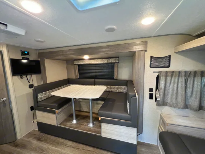 RV rental interior: U-shaped dinette with modern seating, a table, and a TV on the wall.. Coachman Catalina Catalina Summit Series 7 184BHS 2022