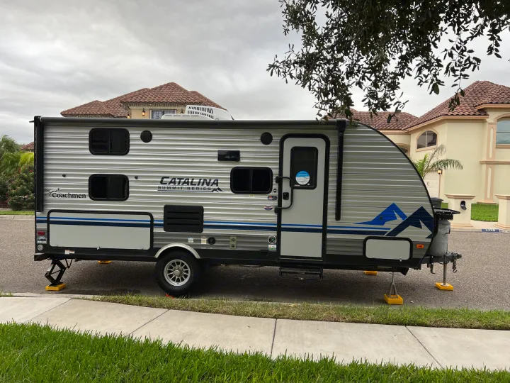 Coachmen Catalina Summit Series travel trailer setup, an ideal RV rental. Parked next to a sidewalk & home.. Coachman Catalina Catalina Summit Series 7 184BHS 2022