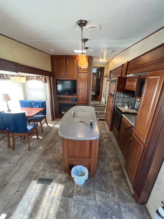 Spacious RV rental interior featuring a full kitchen island, dining area, and cozy living space with a fireplace.. Keystone Cougar 2013