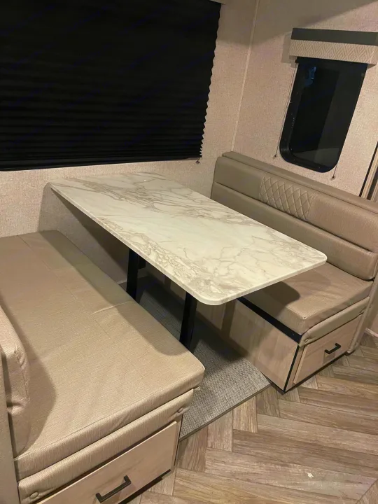 Modern RV rental dinette with cozy booth seating, storage drawers, and a chic faux marble tabletop.. Della Terra 312H Della Terra 2023