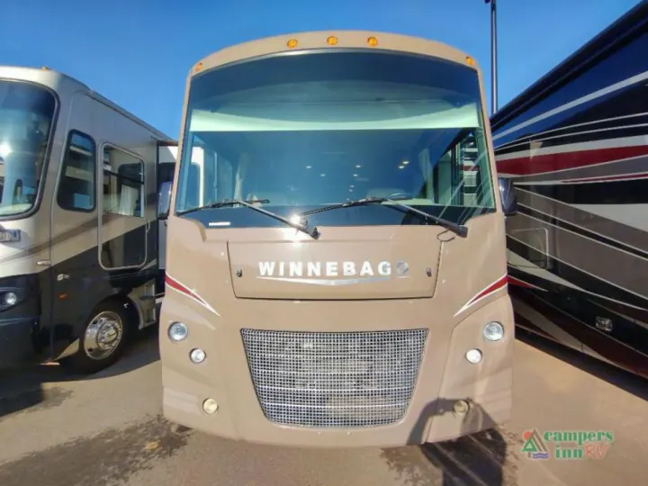 Front view of a beige Winnebago RV, perfect for an rv rental. It's parked with other motorhomes on a sunny day.. Winnebago Vista 2017