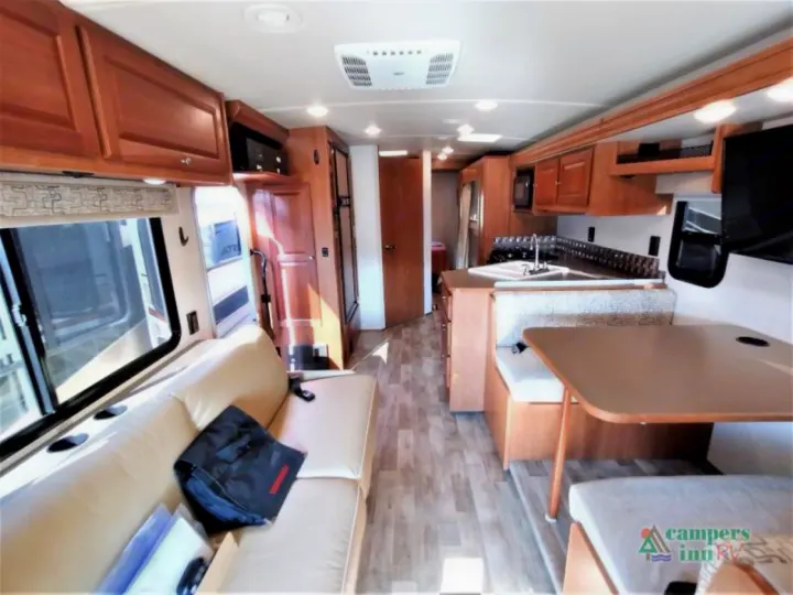 View inside an RV rental showing the comfortable living area with sofa, dining booth, and equipped kitchen.. Winnebago Vista 2017