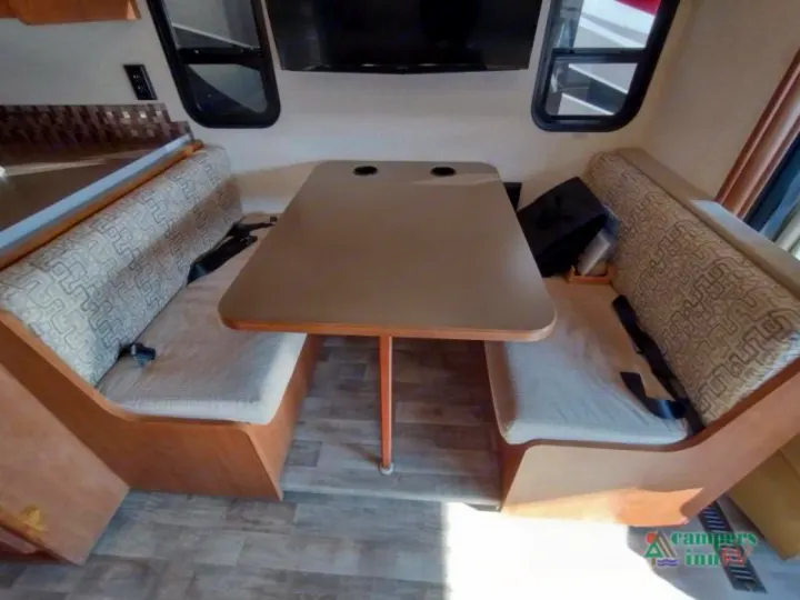RV rental interior: dinette featuring two patterned benches, a central table, and wall-mounted TV, perfect for on-road comfort.. Winnebago Vista 2017