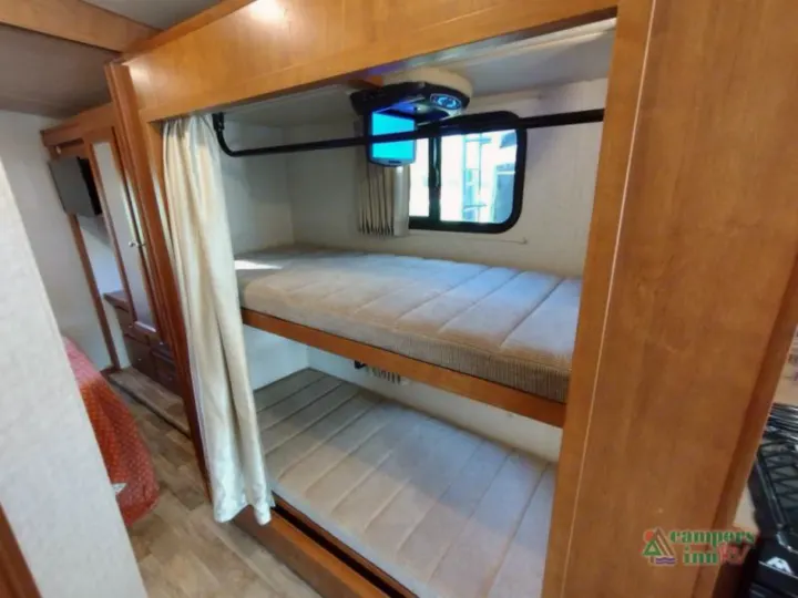 Cozy RV rental interior with bunk beds, overhead TV, and window. Perfect for family adventures.. Winnebago Vista 2017