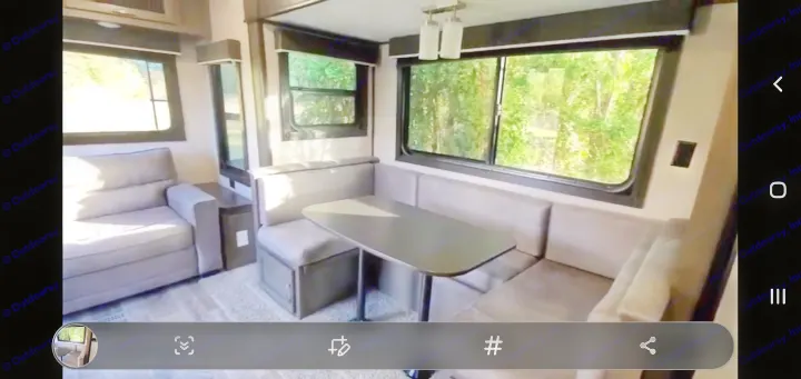 RV rental: Modern interior with gray sofa, U-shaped dinette, and large windows showing green trees. Ideal for travel.. Jayco Jay Flight SLX Rocky Mountain Edition 2021