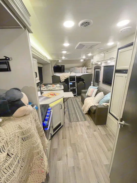 Explore this bright, modern rv rental interior. Features a full kitchen, comfortable living area, and cab-over bunk bed with ladder.. Entegra Coach Odyssey 2023