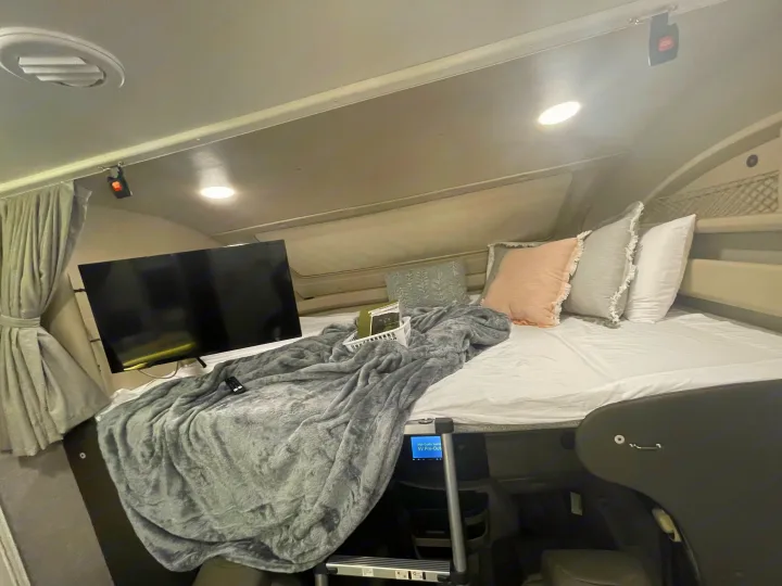 Cozy RV rental bedroom features a comfy bed with soft blankets, pillows, and a TV, ideal for comfortable travel.. Entegra Coach Odyssey 2023