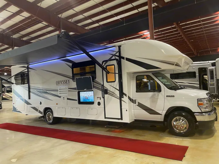 White Entegra Odyssey RV rental: a spacious motorhome with an extended awning, outdoor TV, and sleek design.. Entegra Coach Odyssey 2023