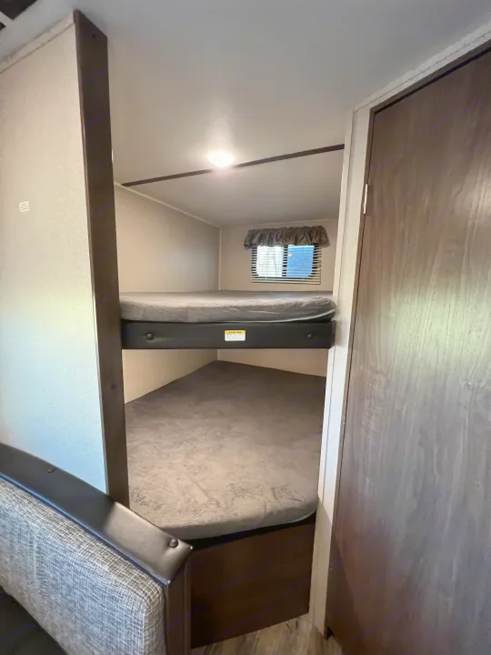 RV rental featuring cozy bunk beds, a window, and ceiling light – perfect for travel trailer camping.. Keystone RV Hideout LHS 2020