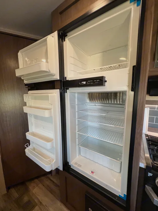 Inside an RV rental's clean Norcold refrigerator and freezer, showing empty shelves and door bins, ready for your food.. Keystone RV Hideout LHS 2020