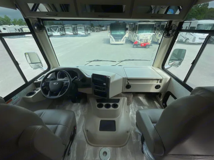 Experience comfort in this RV rental's cockpit, featuring a steering wheel, modern dash, and a clear view of parked motorhomes.. Ford Windsport 2023