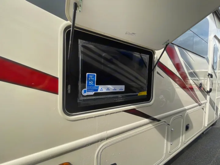 This RV rental boasts an outdoor 32" HD entertainment TV with a built-in soundbar, visible in an open side compartment.. Ford Windsport 2023