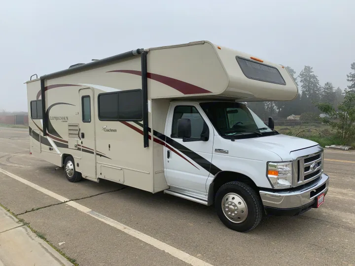 A tan Coachmen Leprechaun Class C RV rental, built on a Ford E-450 chassis, parked on a road. Ready for travel.. Forest River Coachmen Leprechaun 2020