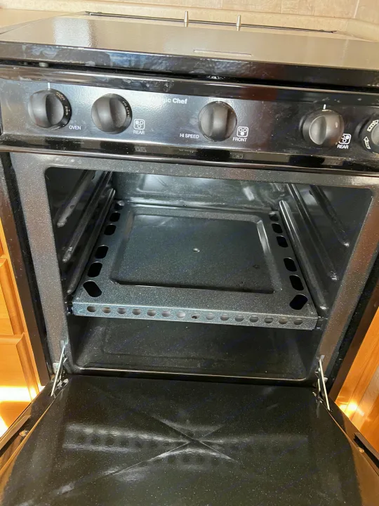 A black Magic Chef RV oven and stove with visible controls and an oven rack. Ideal for an RV rental.. Ford Bounder 2008