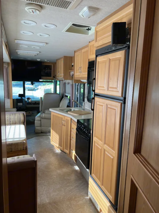 Spacious RV rental interior with a light wood kitchenette, dining area, and front cabin views.. Ford Bounder 2008