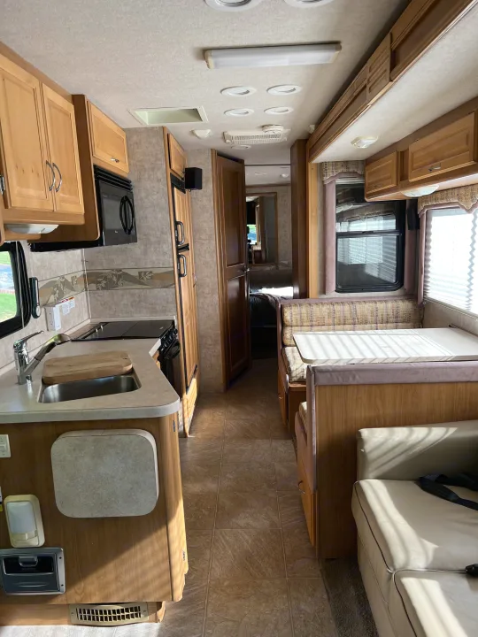 Spacious rv rental interior showing kitchen, dining booth, and living area, with a hallway leading to the rear.. Ford Bounder 2008
