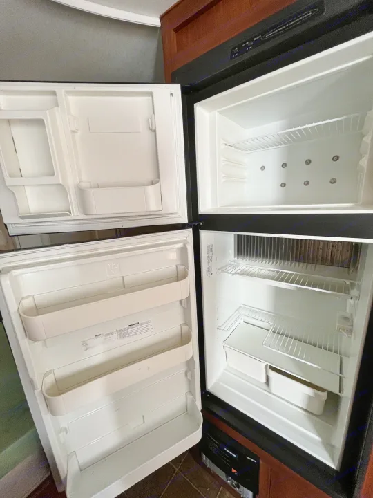 Open, spotless RV rental refrigerator: top freezer, bottom fridge, wire shelves. Ready for your adventure.. Eclipse Recreational Vehicles Milan 2011
