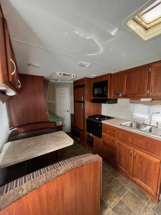 Clean RV rental interior featuring a well-equipped kitchen, comfortable dinette seating, and ample storage space.. Eclipse Recreational Vehicles Milan 2011