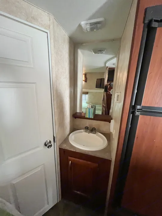 RV rental interior shows a compact bathroom sink, mirror, and door, designed for efficient use of space.. Eclipse Recreational Vehicles Milan 2011