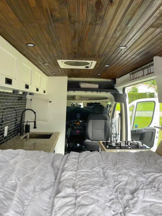 Modern RV rental: interior with cozy bed, kitchen area with black tile backsplash & sink, plus the driver's cabin.. Other Other 2020