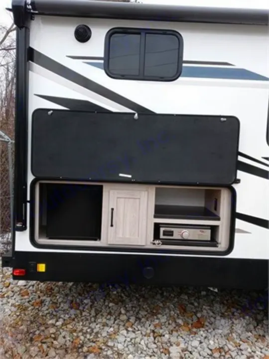 This RV rental features an open outdoor kitchen with a mini-fridge, cabinet, and built-in griddle, ideal for camping.. Heartland RVs Sundance Ultra Lite 2022