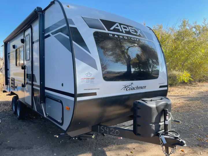 A white Coachmen Apex Nano travel trailer, ideal for an RV rental, parked outdoors under a clear sky.. Coachmen Apex 208BHS 2023
