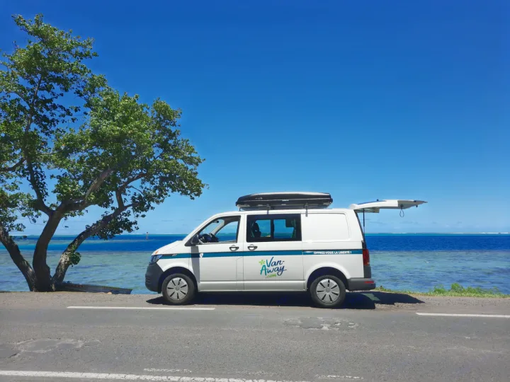White RV rental van parked oceanside under a clear blue sky, rear hatch open. Ideal for a serene coastal road trip.. Volkswagen Transporter T6.1 2021