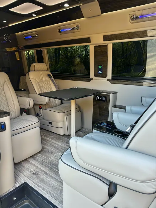 RV rental with a luxurious, spacious interior: quilted light leather seats, table, wood floor, and tech controls.. Midwest Automotive Designs Ultimate Coach 2023