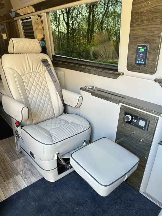 Relax in this luxurious RV rental: features an ergonomic leather seat, footrest, and integrated tech controls for comfort.. Midwest Automotive Designs Ultimate Coach 2023