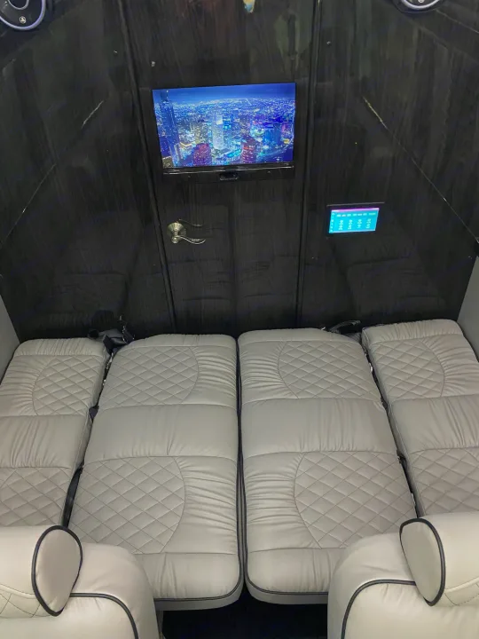 Luxury RV rental interior: spacious cabin with plush grey quilted beds, entertainment TV, and control panel. Ideal for travel.. Midwest Automotive Designs Ultimate Coach 2023