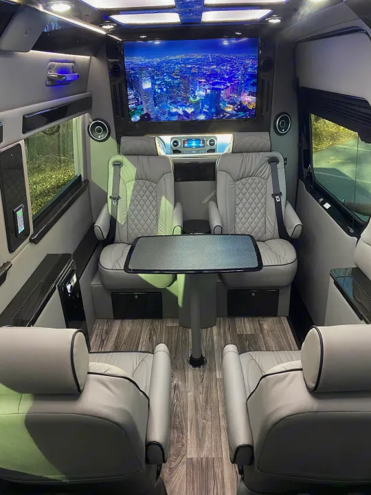 Explore this spacious luxury van interior for your next RV rental. Features premium leather seats, large entertainment screen, and table.. Midwest Automotive Designs Ultimate Coach 2023