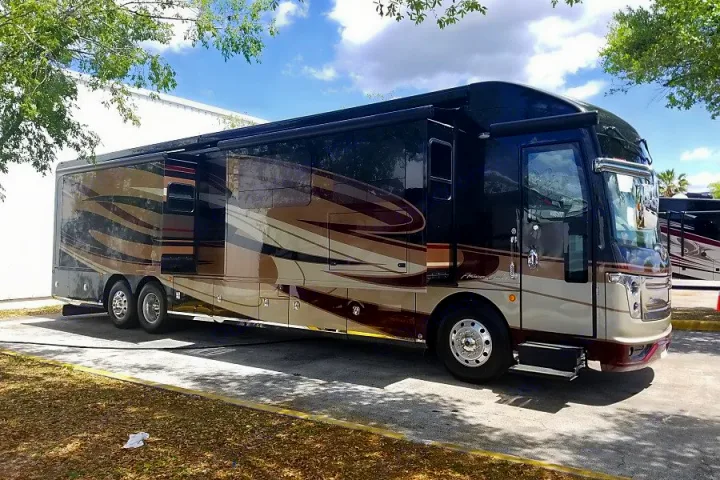 A large, luxurious RV, featuring black, brown, and beige design, parked outdoors. Perfect for your next RV rental.. American Coach American Eagle 2017